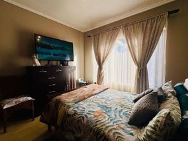 A cozy bedroom featuring laminate flooring and a window dressed with curtains, providing a comfortable and functional sleeping space.