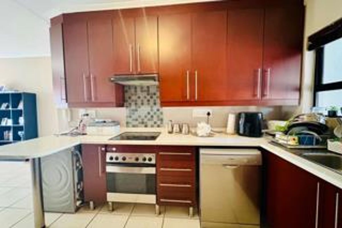 A functional kitchen featuring dark wood cabinetry, a mosaic tile backsplash, built-in oven and hob, and ample counter space for meal preparation.
