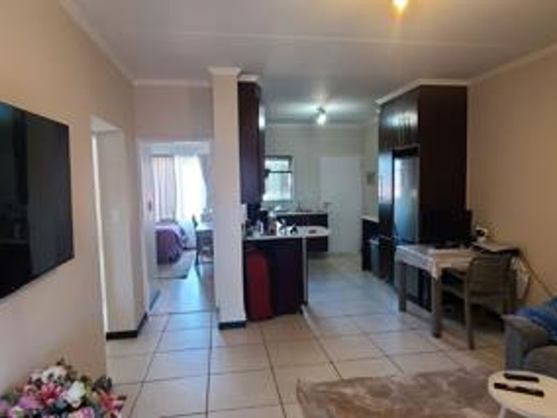 Open plan living and kitchen area featuring tiled flooring, built-in cabinetry, and a functional layout connecting to the bedroom space.
