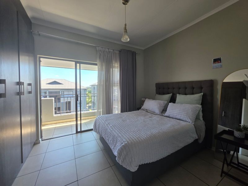 A well-maintained bedroom featuring tiled flooring, built-in cupboards, and a sliding glass door providing direct access to a private balcony.