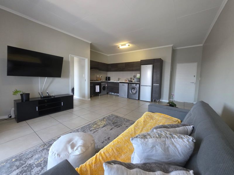 Open plan living area featuring a modern kitchen with dark cabinetry, tiled flooring, and a seamless flow into the lounge space.