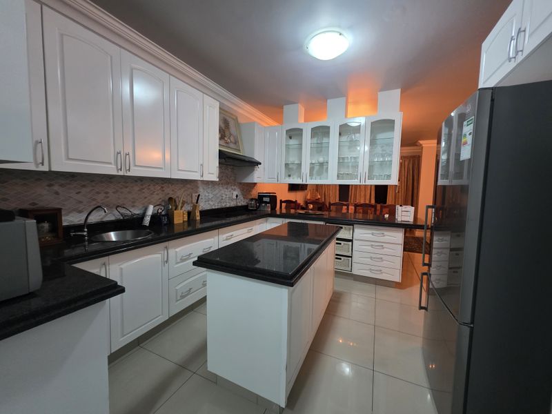 A well-maintained kitchen featuring white cabinetry, granite countertops, a central island, and a mosaic tile backsplash, offering a clean and functional cooking space.