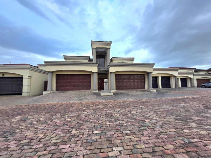 Front elevation of a multi-garage apartment complex featuring a paved driveway, covered entrance, and architectural columns.