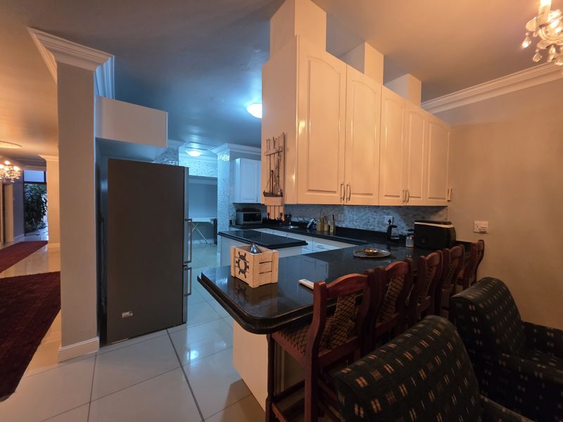 A functional kitchen featuring granite countertops, ample built-in cabinetry, and a breakfast bar, seamlessly integrated into the open-plan living area.