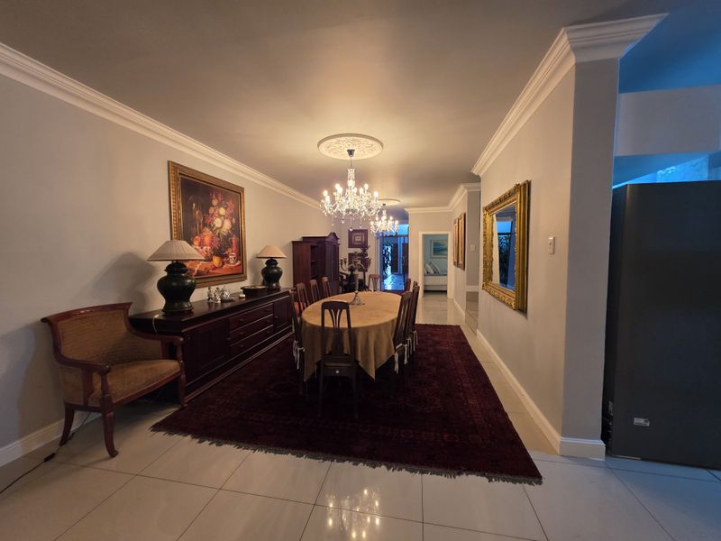 Spacious dining room featuring elegant crown molding, a decorative ceiling rose, and polished tiled flooring, creating a formal atmosphere for entertaining.