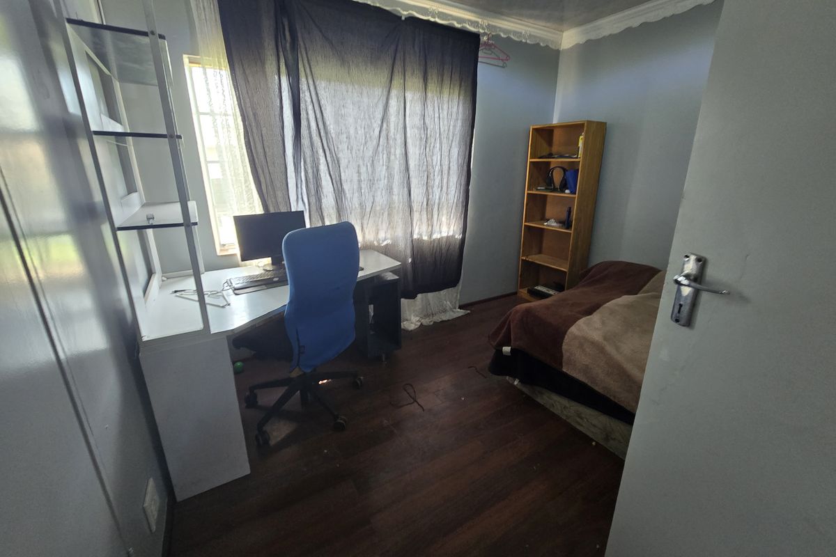 A functional bedroom featuring laminate flooring and decorative cornice detailing, offering a versatile space for rest or study.