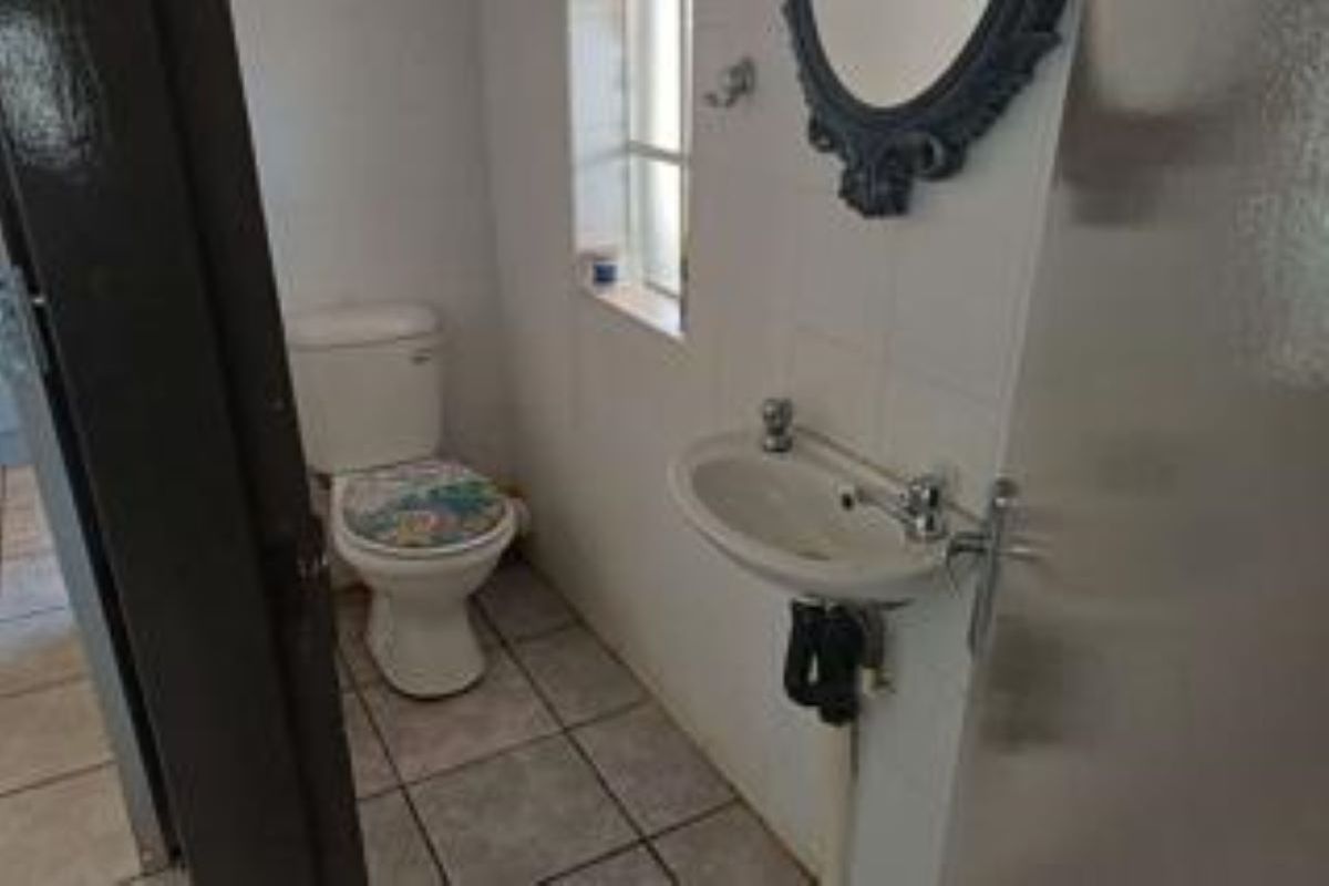 A compact guest bathroom featuring a pedestal basin and toilet with tiled flooring and splashback.
