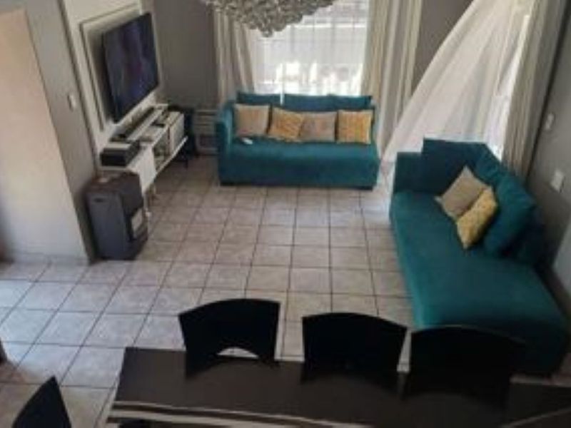 An open-plan living and dining area featuring tiled flooring and neutral wall tones, providing a functional space for relaxation and entertaining.