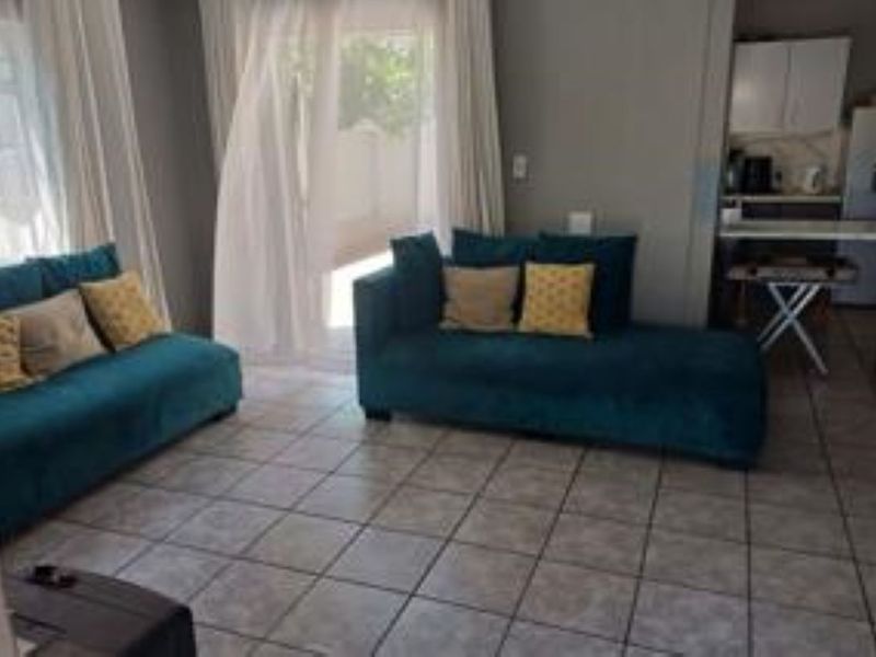 Open plan living area featuring tiled flooring and a sliding glass door leading to the exterior, with an adjacent kitchen space.