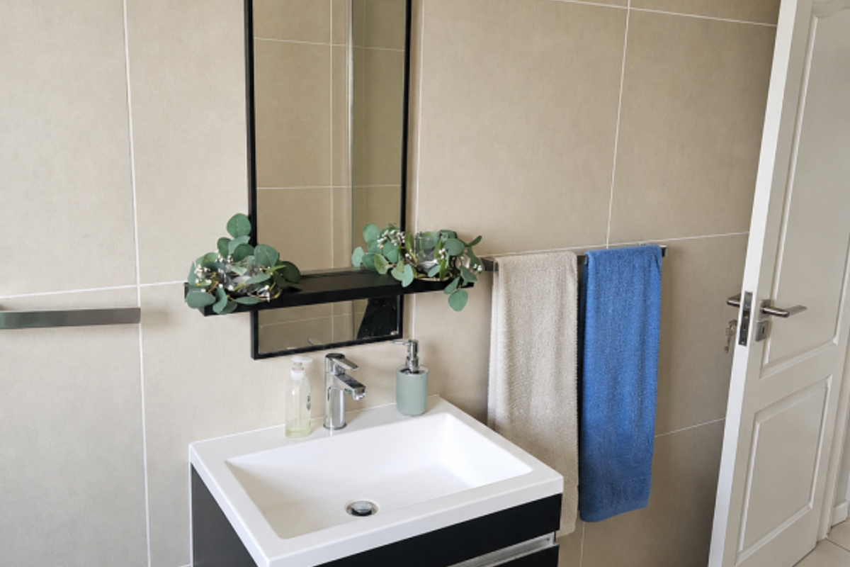 A modern bathroom featuring a wall-mounted black vanity with a white ceramic basin, chrome tapware, and neutral wall tiling.