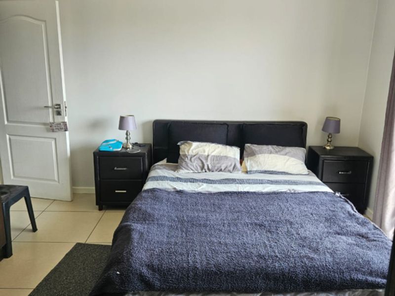 A functional bedroom featuring neutral tiled flooring and a standard interior door, providing a clean and simple living space.