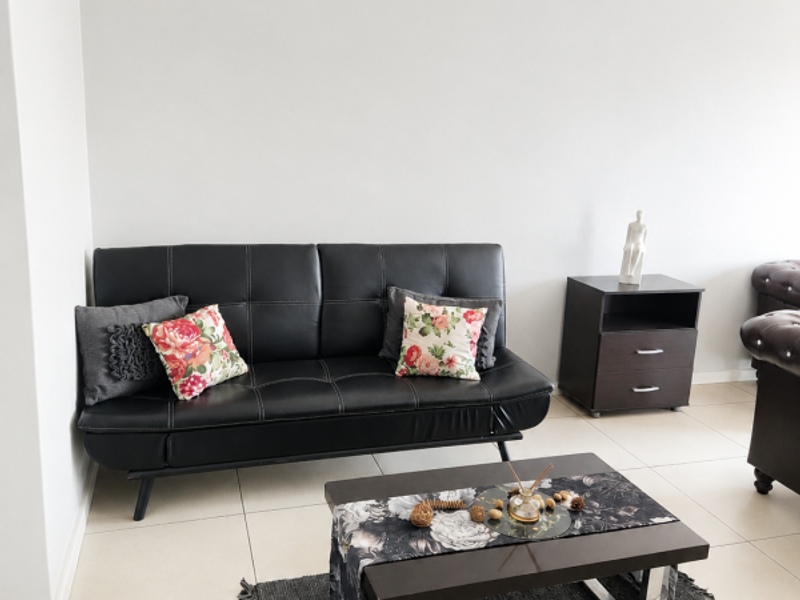 A bright living room featuring neutral wall tones, clean tiled flooring, and a coved ceiling, providing a simple and functional space.