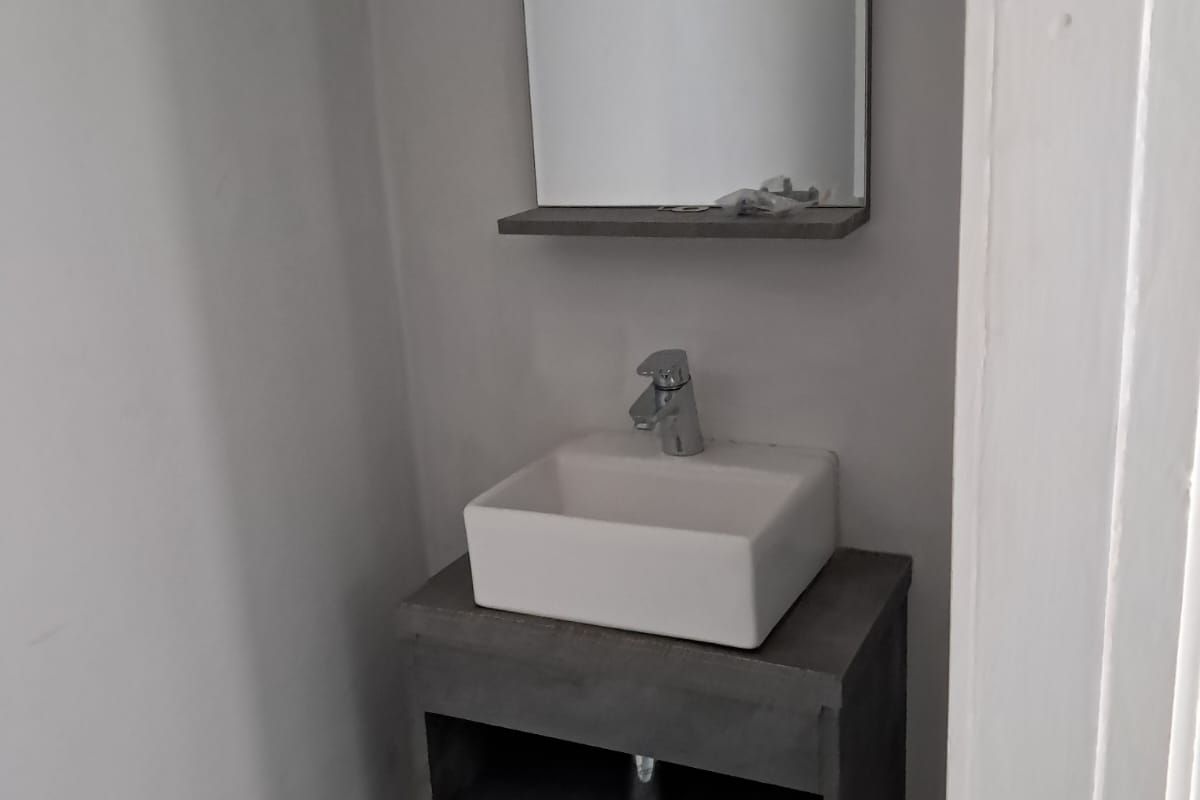 A compact bathroom featuring a modern wall-mounted vanity with a vessel sink, chrome mixer tap, and a matching wall mirror.