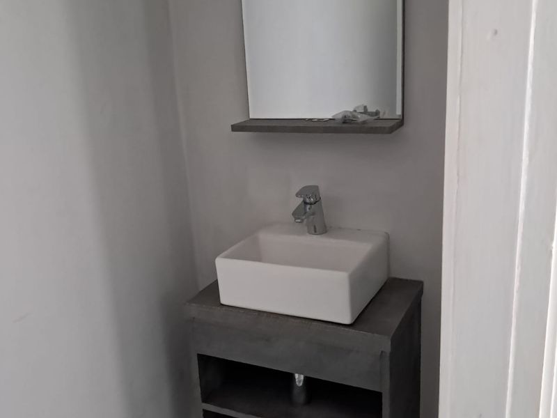 A compact bathroom featuring a modern wall-mounted vanity with a vessel sink, chrome mixer tap, and a matching wall mirror.