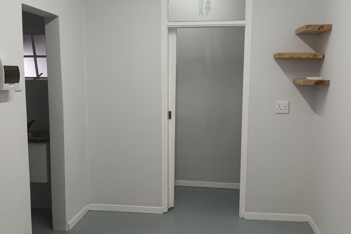 A clean, neutral hallway featuring floating wooden shelves, an air conditioning unit, and a doorway leading to an adjacent room.