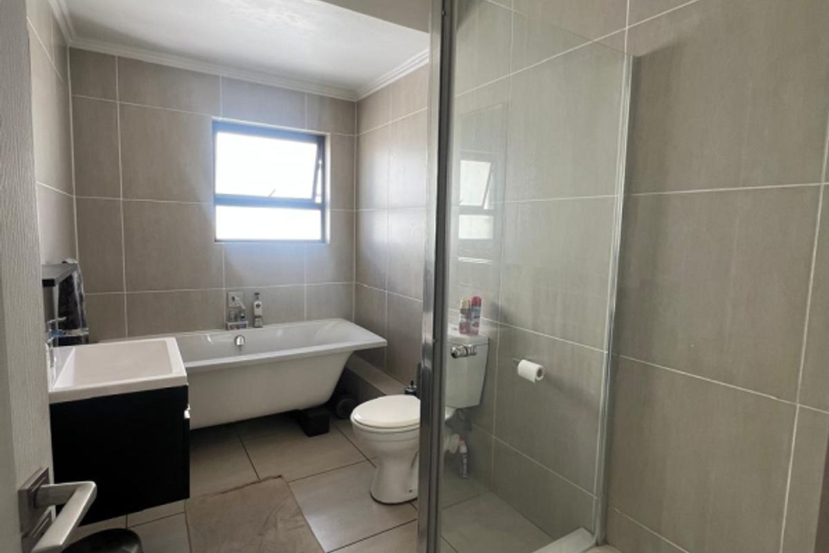 Modern bathroom featuring a freestanding bathtub, separate glass-enclosed shower, vanity cabinet, and neutral floor-to-ceiling tiling.