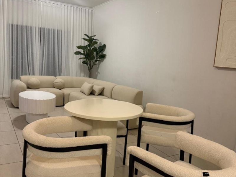 A neutrally decorated living area featuring tiled flooring and a ceiling-mounted light fixture, providing a functional and open space for relaxation.