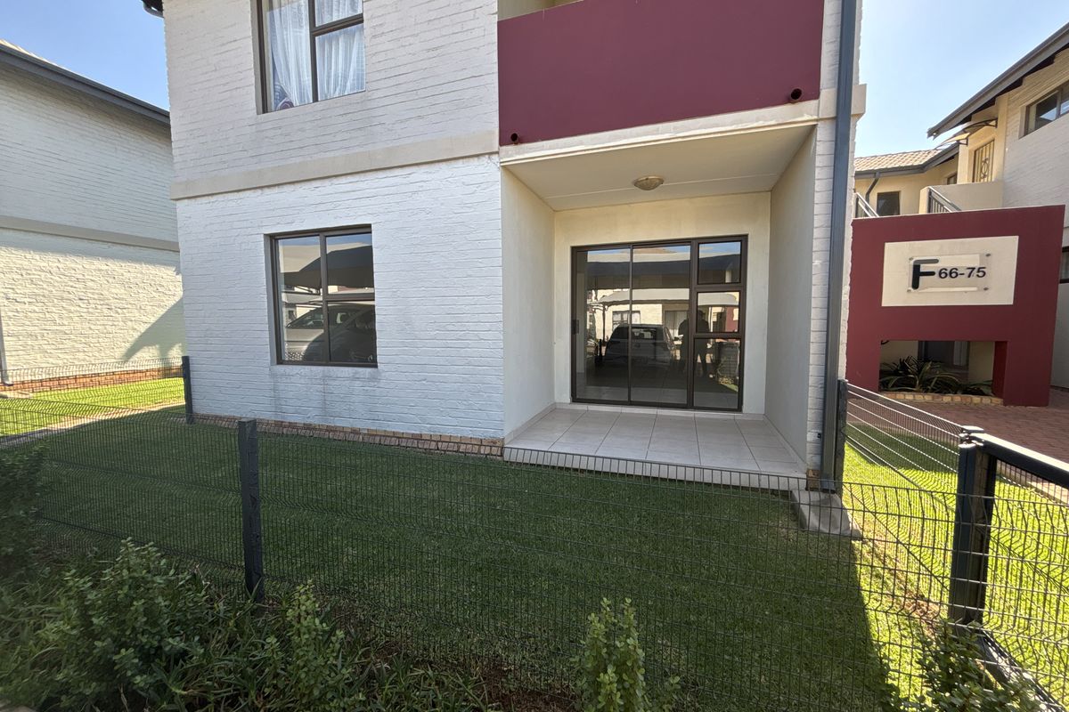 Rear view of a townhouse featuring a tiled patio, sliding glass doors, and a private fenced garden area.