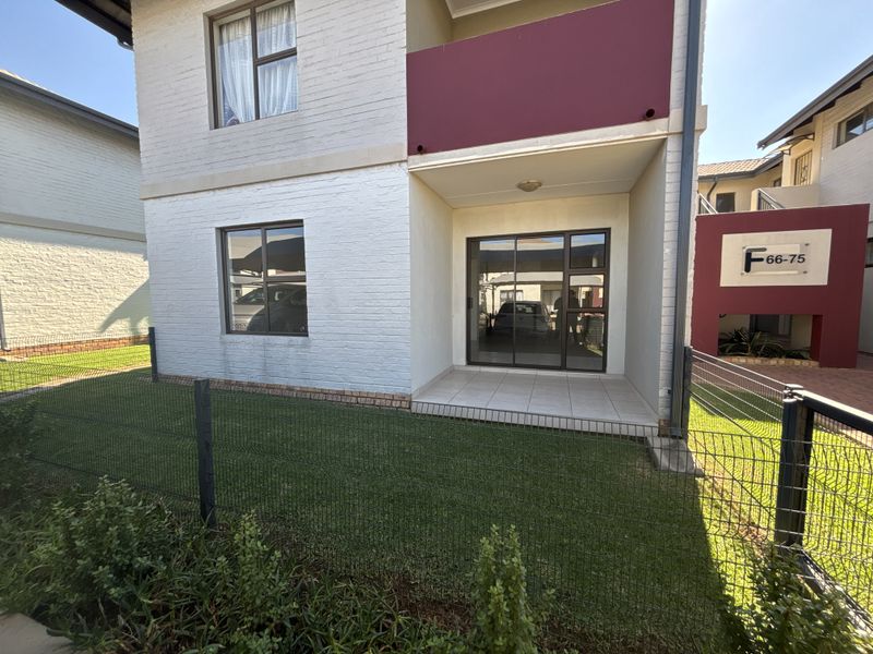 Rear view of a townhouse featuring a tiled patio, sliding glass doors, and a private fenced garden area.