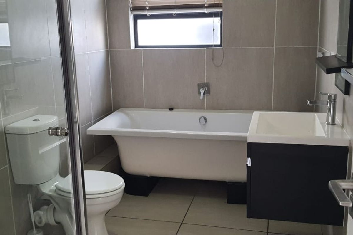 Modern bathroom featuring a freestanding bathtub, glass-enclosed shower, wall-mounted toilet, and a sleek vanity cabinet with a basin.