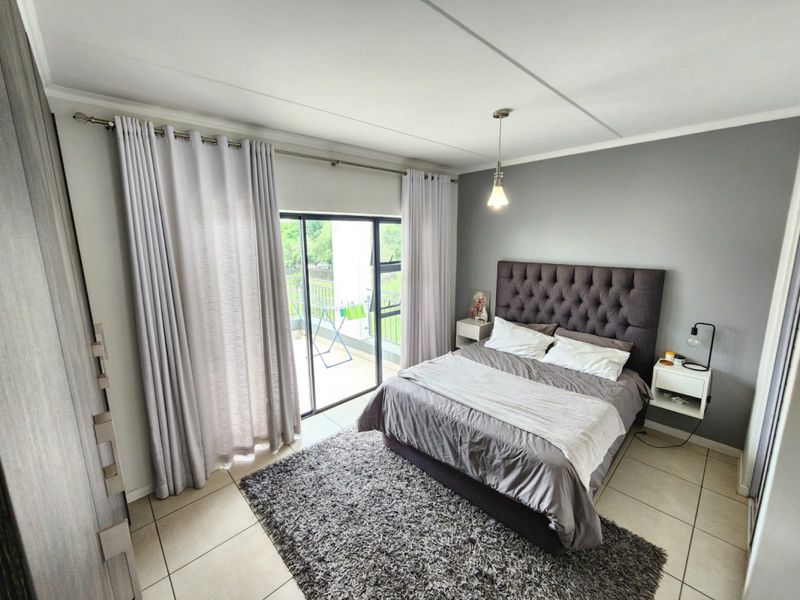 A well-maintained bedroom featuring tiled flooring, a built-in wardrobe, and a sliding glass door providing access to a private balcony.
