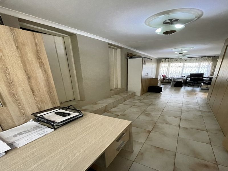 Spacious living area featuring tiled flooring, built-in cabinetry, and a raised floor section, offering a versatile layout for various living arrangements.