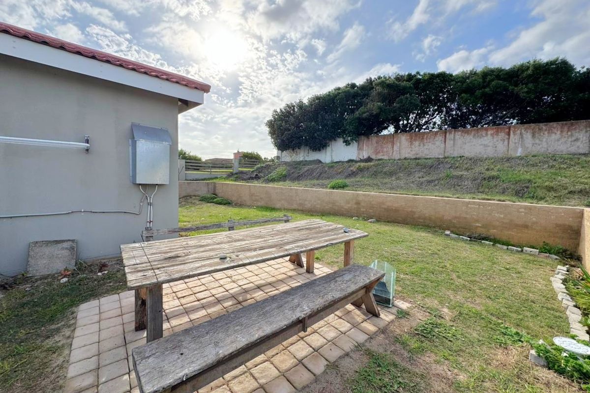 Rear garden area featuring a paved patio section, retaining wall, and boundary wall, offering potential for landscaping and outdoor living improvements.