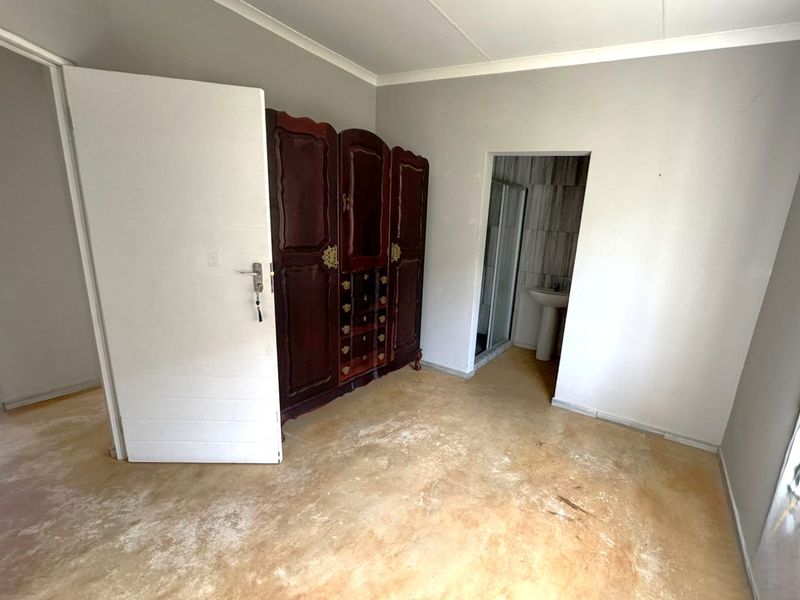 Bedroom featuring exposed concrete flooring and an en-suite bathroom with a pedestal basin and shower enclosure.