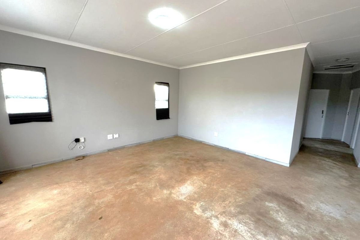 An empty living room featuring grey painted walls, a flush mount ceiling light, and an unfinished concrete floor.