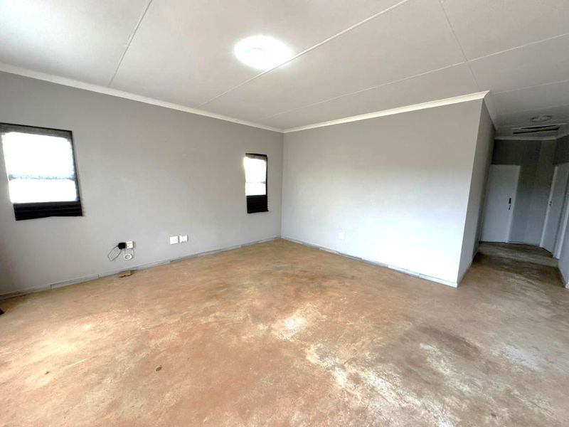 An empty living room featuring grey painted walls, a flush mount ceiling light, and an unfinished concrete floor.
