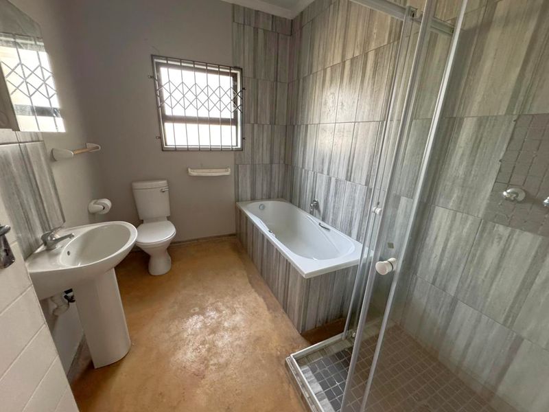 A functional bathroom featuring a pedestal basin, toilet, bathtub, and separate shower enclosure with tiled wall finishes.