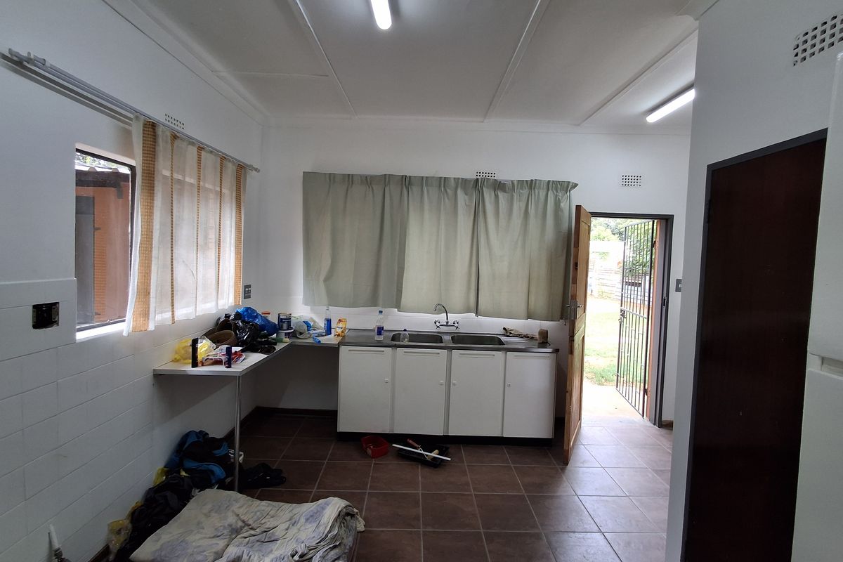 A functional kitchen area featuring tiled flooring, built-in base cabinetry with a double basin sink, and direct access to the exterior.