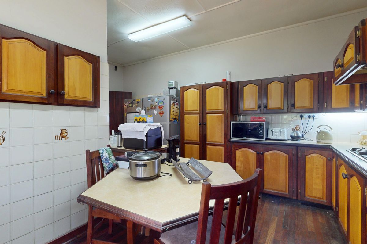A functional kitchen featuring traditional two-tone wooden cabinetry, tiled splashbacks, and a gas hob, offering a classic layout with potential for modern updates.