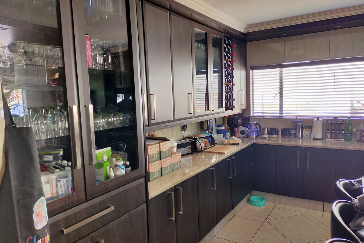 A functional kitchen featuring dark wood cabinetry, granite countertops, glass-front display units, and tiled flooring, offering ample storage and workspace.