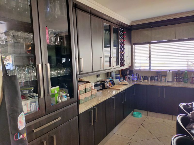 A functional kitchen featuring dark wood cabinetry, granite countertops, glass-front display units, and tiled flooring, offering ample storage and workspace.