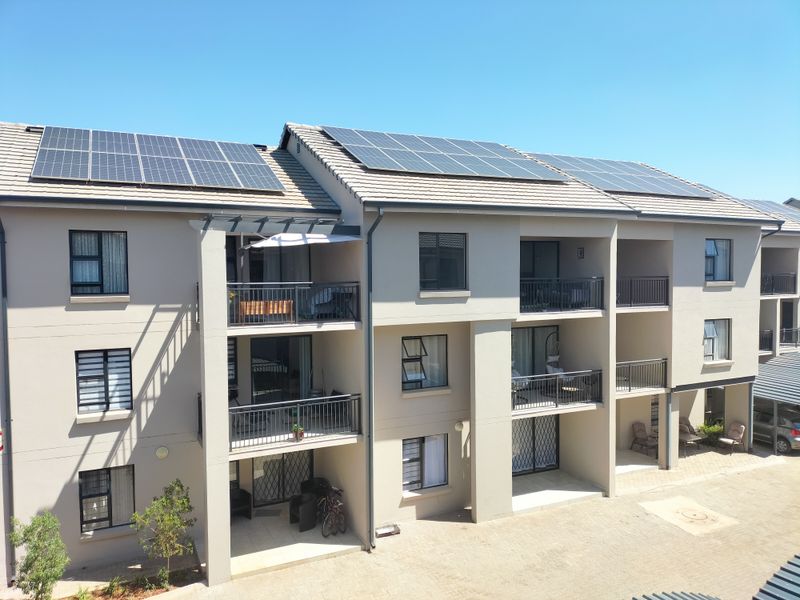 A modern apartment building exterior featuring multiple balconies, large windows, and a roof equipped with solar panels.