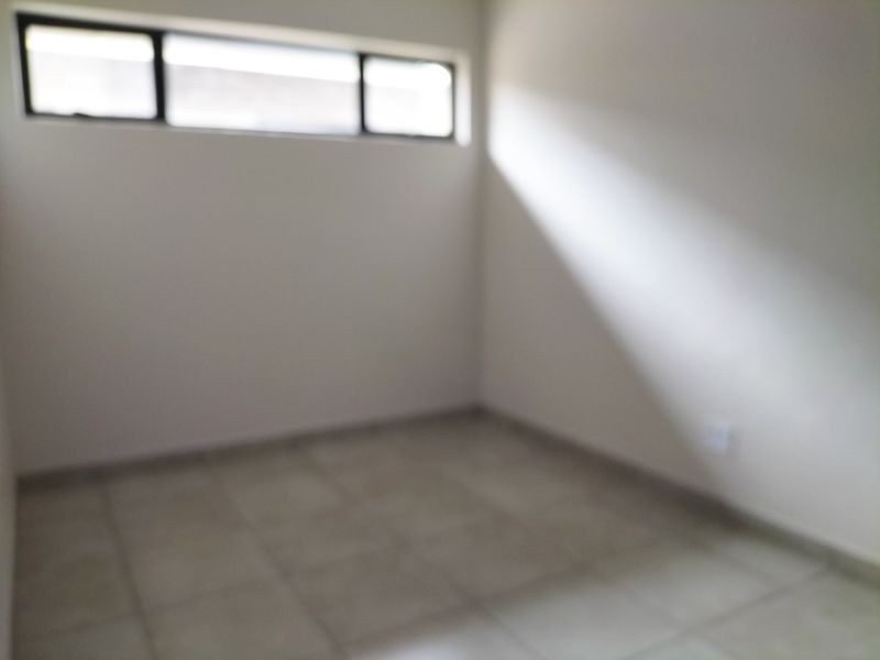 An empty bedroom featuring tiled flooring and a high-level window, providing a neutral space ready for personalization.