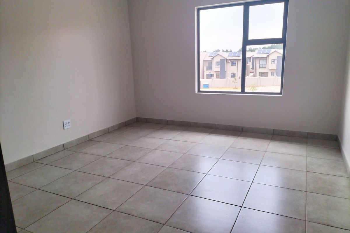 A clean, empty bedroom featuring neutral tiled flooring, modern aluminium window frames, and smooth wall finishes, ready for personalization.