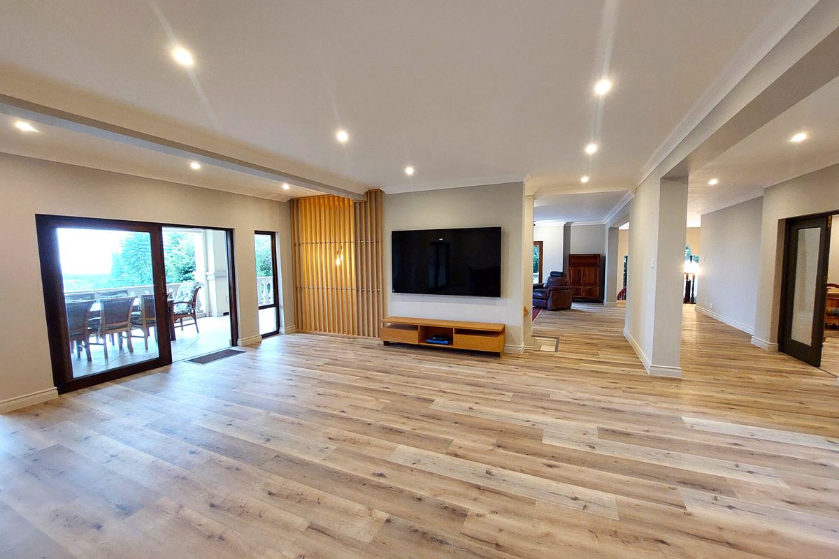 Spacious living room featuring modern timber laminate flooring, recessed downlights, and a decorative timber slat feature wall with direct access to an outdoor patio.