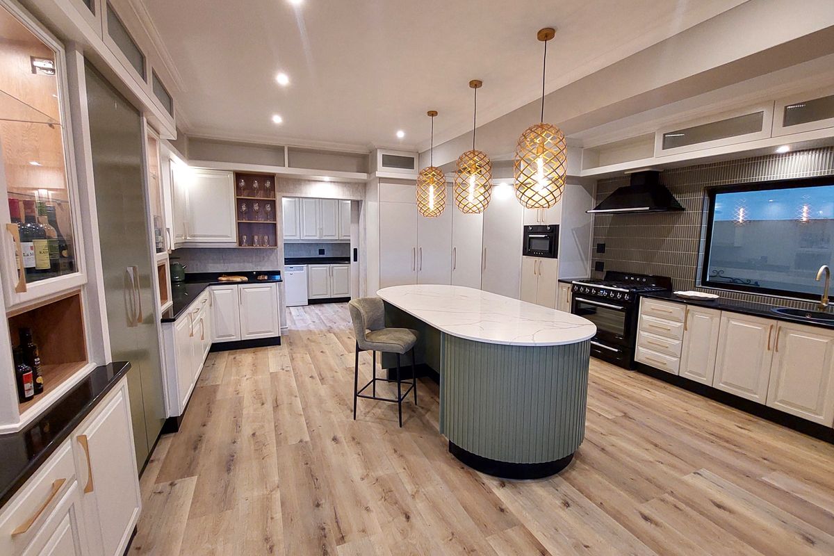 Modern, high-end kitchen featuring a central island with quartz countertop, premium gas range, integrated cabinetry, and stylish pendant lighting.