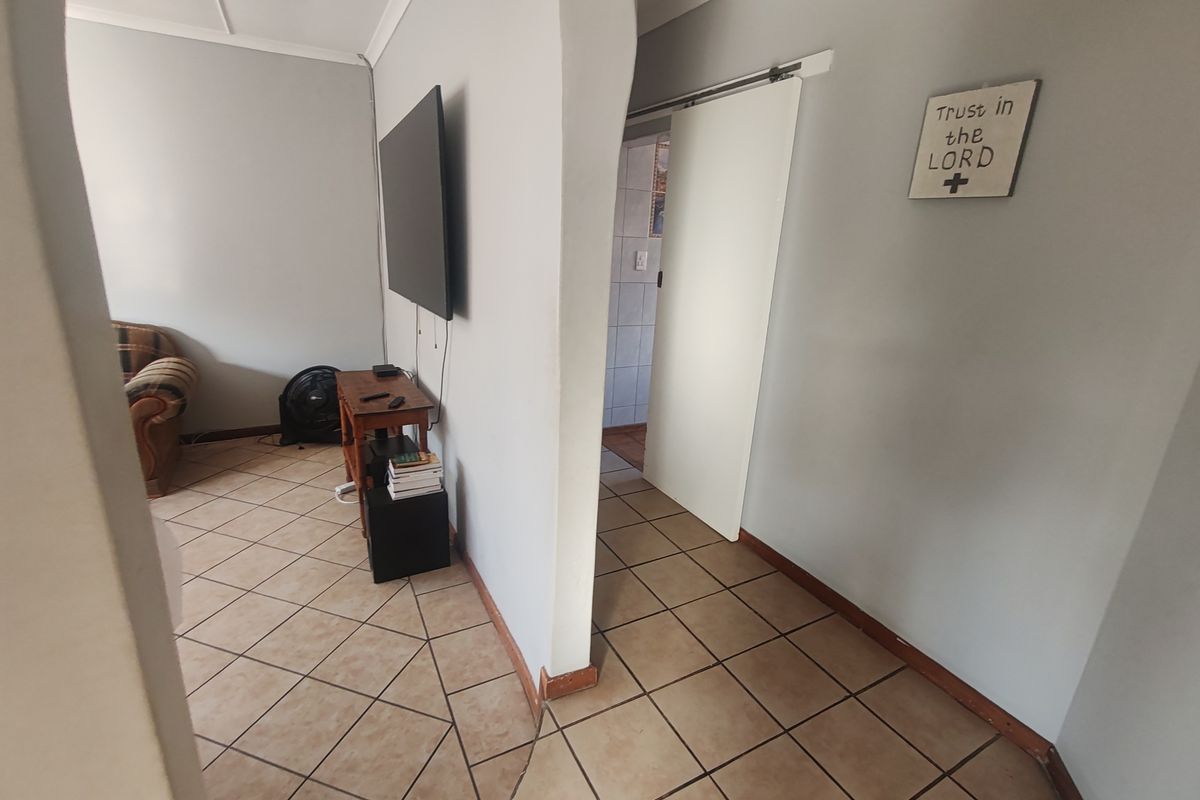 A living area featuring ceramic tile flooring, an arched transition, and a sliding barn door leading to an adjacent room.