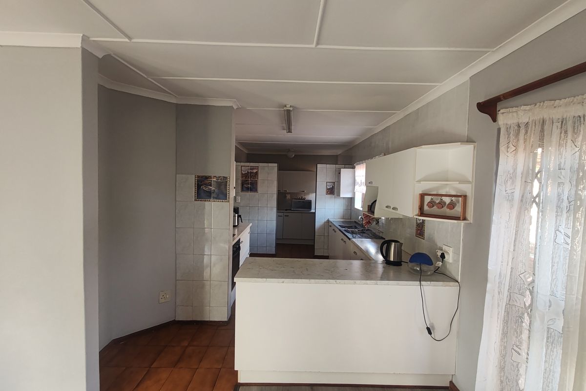A functional kitchen featuring built-in cabinetry, laminate countertops, and a tiled splashback, offering a practical layout with potential for modern updates.