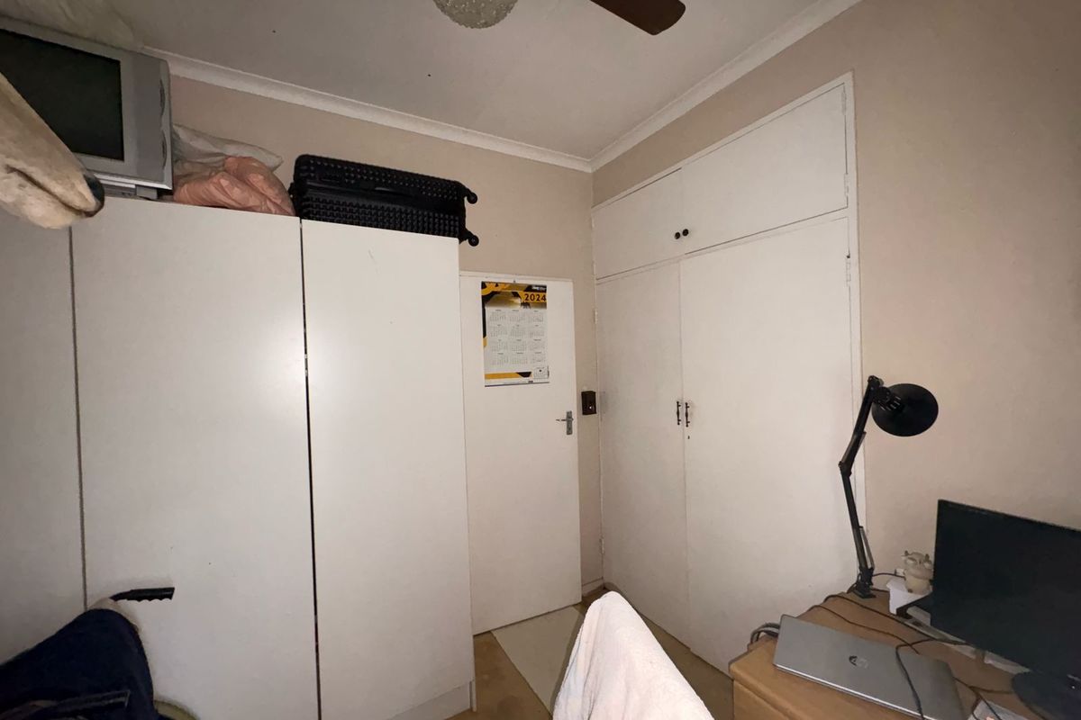 A bedroom featuring built-in cupboards and a ceiling fan, providing functional storage and overhead ventilation.