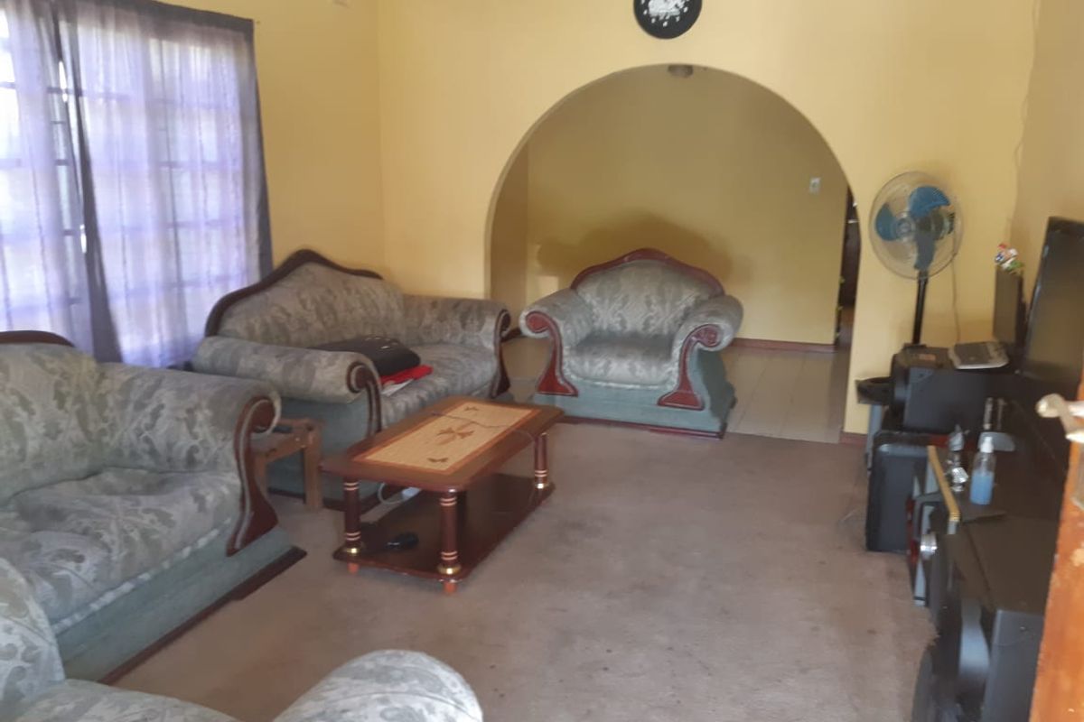 A living room featuring an arched doorway leading to an adjacent space, with carpeted flooring and yellow wall finishes.