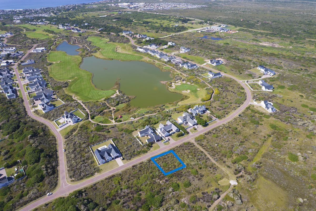 Aerial view of a vacant residential plot situated within a coastal estate, featuring road access and proximity to local golf course and water features.