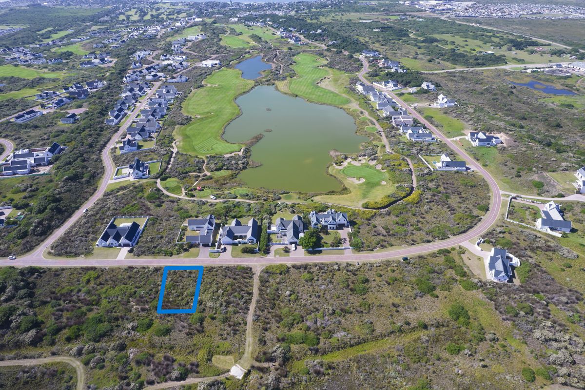 Aerial view of a vacant residential plot situated within a developed estate, featuring surrounding natural landscape and proximity to a golf course.