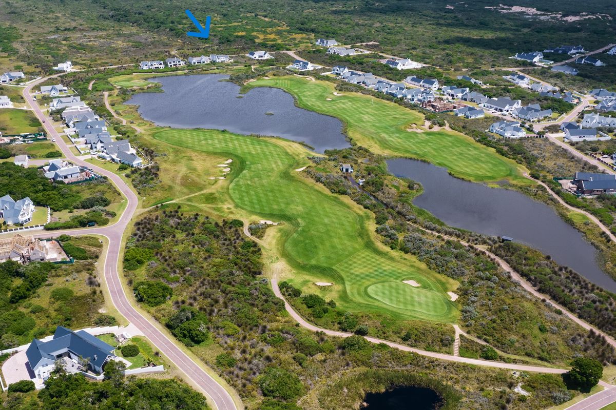 An aerial view of a residential golf estate featuring manicured fairways, natural lakes, and surrounding coastal vegetation.