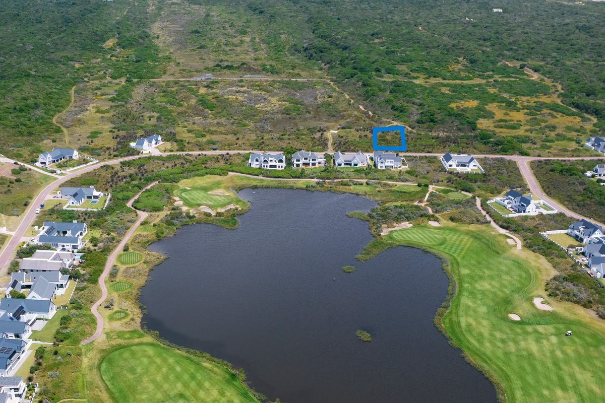 Aerial view of a vacant residential land plot situated within a golf estate, featuring proximity to a lake and surrounding natural landscape.
