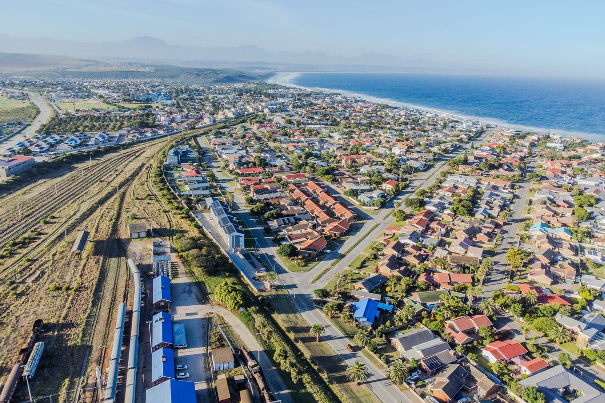 An aerial view of a coastal residential suburb featuring proximity to the coastline, railway infrastructure, and established housing developments.