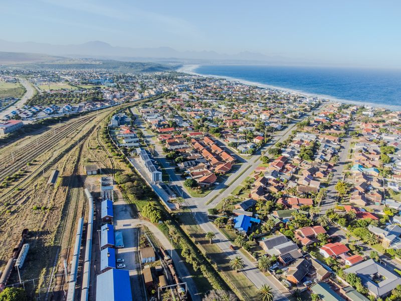 An aerial view of a coastal residential suburb featuring proximity to the coastline, railway infrastructure, and established housing developments.